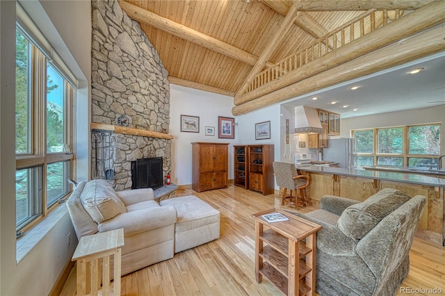 living area with high vaulted ceiling, light wood-style flooring, wood ceiling, a fireplace, and beam ceiling