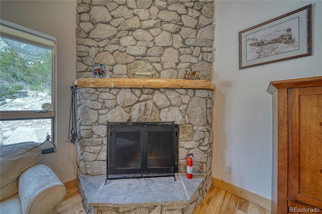 interior details with a fire extinguisher, baseboards, wood finished floors, and a fireplace