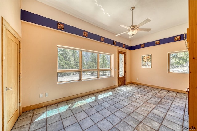 empty room featuring ceiling fan, baseboards, and stone finish flooring