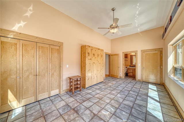 unfurnished bedroom featuring baseboards, a ceiling fan, stone finish floor, and a towering ceiling