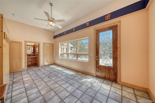 interior space featuring stone finish floor, a ceiling fan, and baseboards