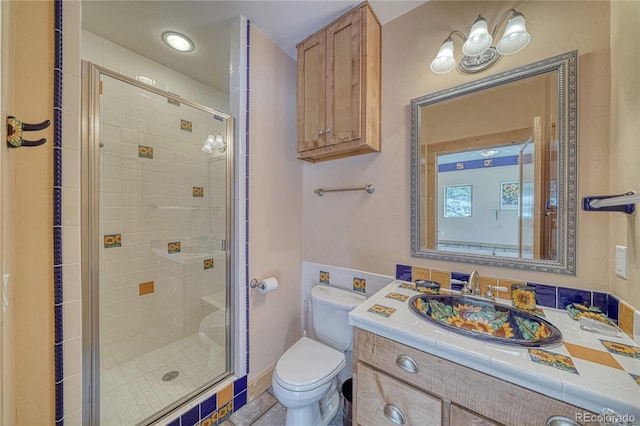 bathroom featuring toilet, vanity, and a stall shower