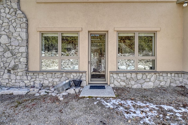 doorway to property with stone siding and stucco siding
