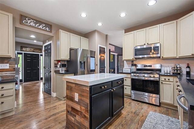 kitchen with a center island, backsplash, appliances with stainless steel finishes, and hardwood / wood-style floors