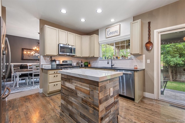 kitchen with hardwood / wood-style flooring, stainless steel appliances, sink, a chandelier, and a center island