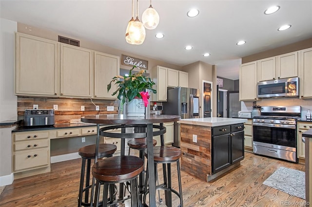 kitchen featuring decorative light fixtures, decorative backsplash, stainless steel appliances, and a kitchen island