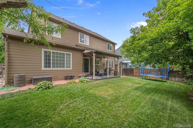 rear view of house with central AC, a trampoline, a patio area, and a yard