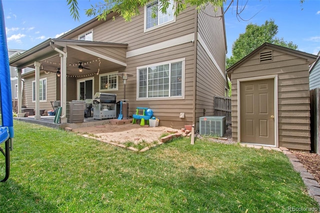 back of property featuring ceiling fan, central AC, a storage unit, and a lawn