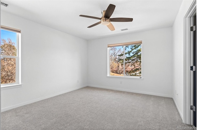 carpeted empty room with visible vents, baseboards, a healthy amount of sunlight, and ceiling fan