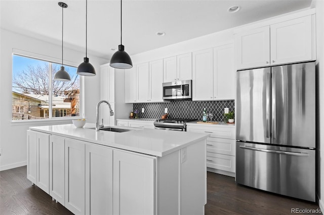 kitchen with dark wood-style floors, a sink, appliances with stainless steel finishes, white cabinetry, and tasteful backsplash