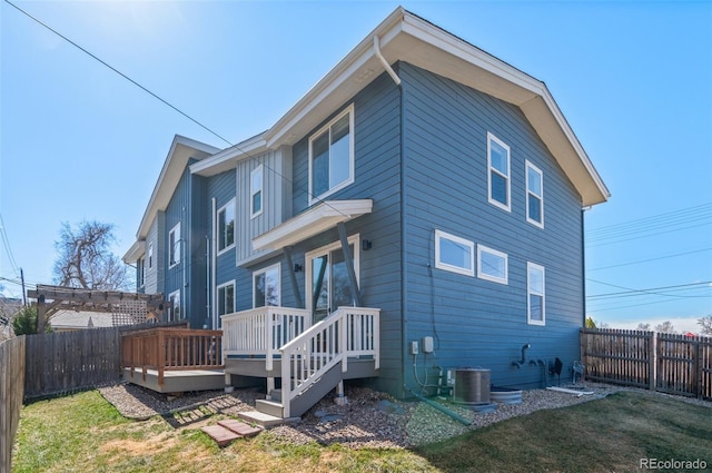 rear view of property featuring a deck, central air condition unit, a yard, and a fenced backyard