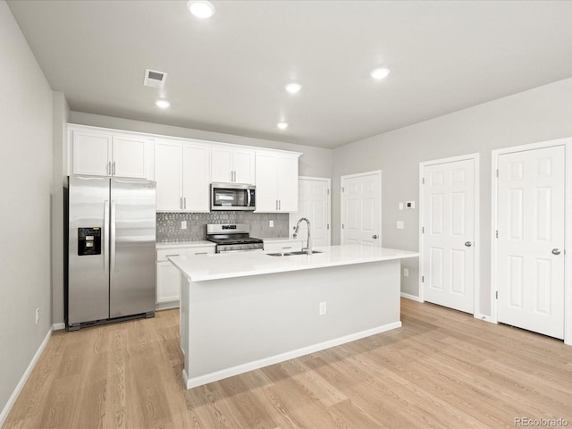 kitchen featuring appliances with stainless steel finishes, sink, light hardwood / wood-style flooring, white cabinetry, and an island with sink