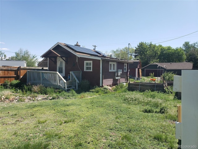 1314 16th Ave, Greeley, CO 80631 - rear view of property with roof mounted solar panels, a wooden deck, and a vegetable garden