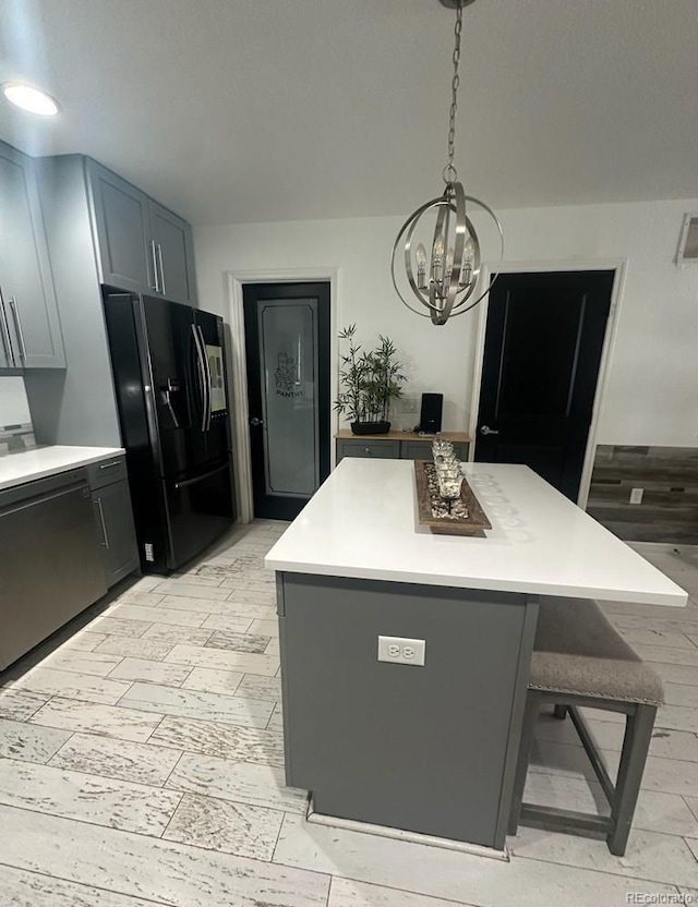 kitchen featuring black refrigerator with ice dispenser, dishwasher, a chandelier, and light countertops