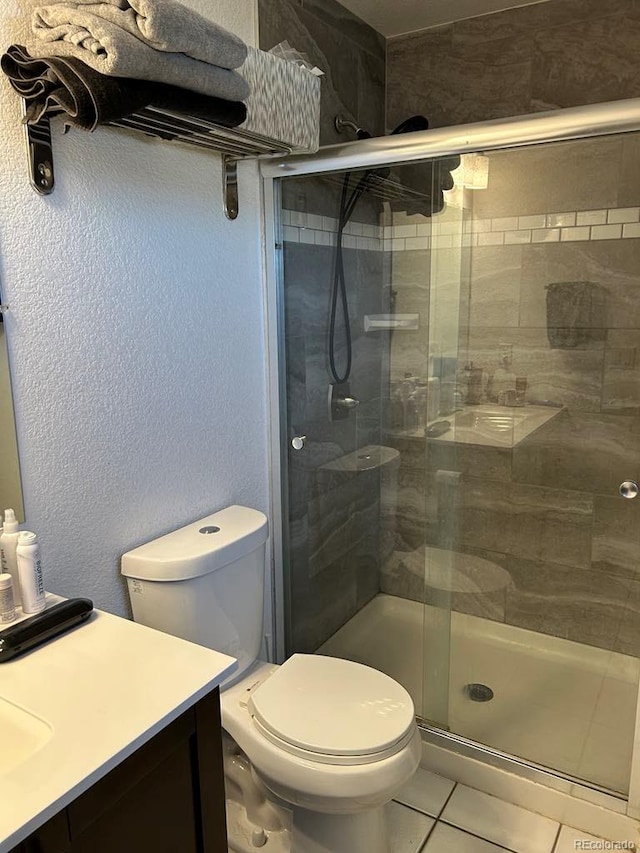 full bathroom with toilet, tile patterned flooring, vanity, a shower stall, and a textured wall