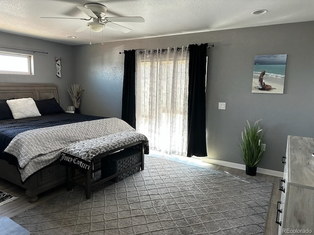 bedroom with wood finished floors, ceiling fan, baseboards, and a textured ceiling