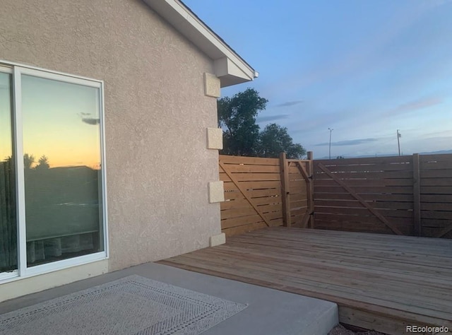 view of property exterior featuring stucco siding, fence, and a wooden deck