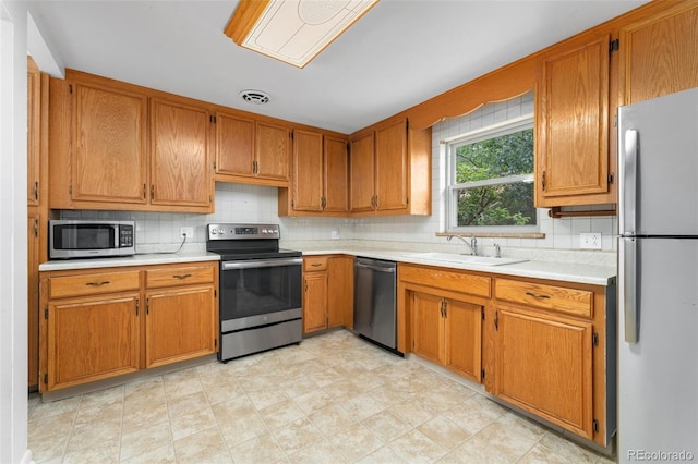 8675 Calvin Dr, Arvada, CO 80002 - kitchen featuring appliances with stainless steel finishes, light countertops, and backsplash