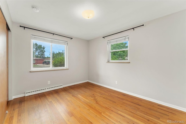 8675 Calvin Dr, Arvada, CO 80002 - unfurnished bedroom featuring baseboard heating, a closet, light wood finished floors, and multiple windows