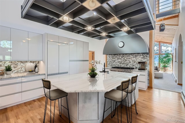 kitchen with a kitchen island with sink, a kitchen bar, and white cabinetry