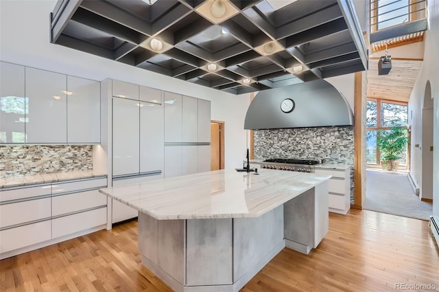 kitchen featuring light stone countertops, a kitchen island with sink, and white cabinetry