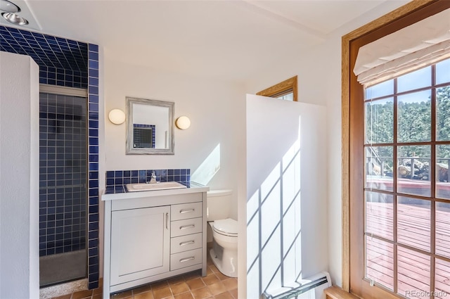 bathroom with vanity, toilet, a tile shower, tile walls, and tile patterned flooring