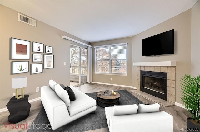 living room with light hardwood / wood-style floors and a tiled fireplace