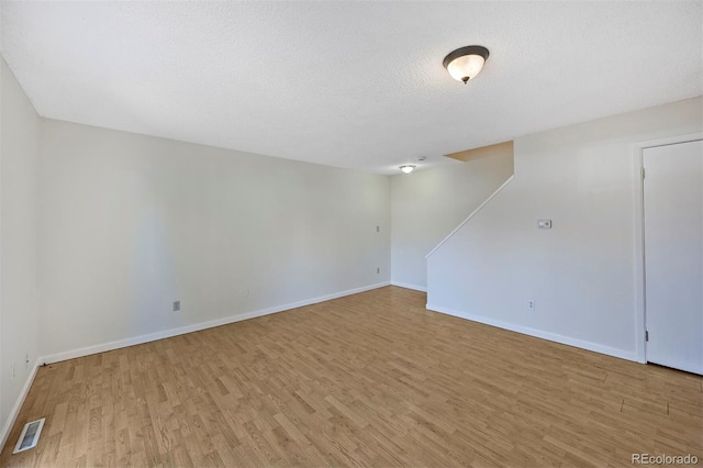 empty room with wood finished floors, baseboards, and visible vents