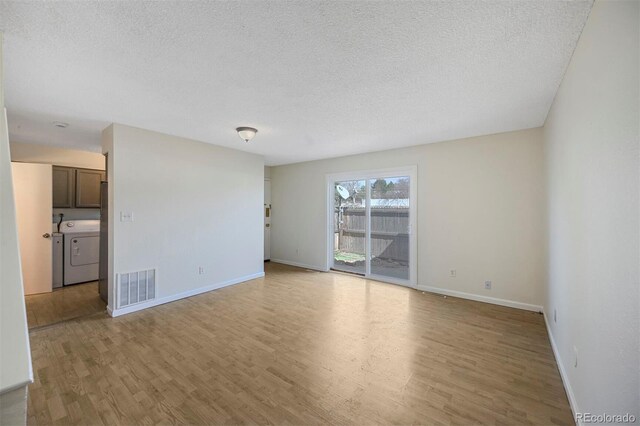 spare room featuring washer and clothes dryer, visible vents, light wood-type flooring, and a textured ceiling