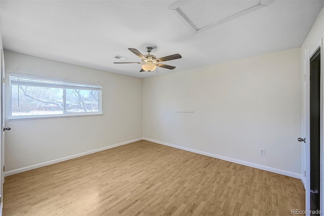 unfurnished room with attic access, baseboards, visible vents, light wood-style flooring, and ceiling fan