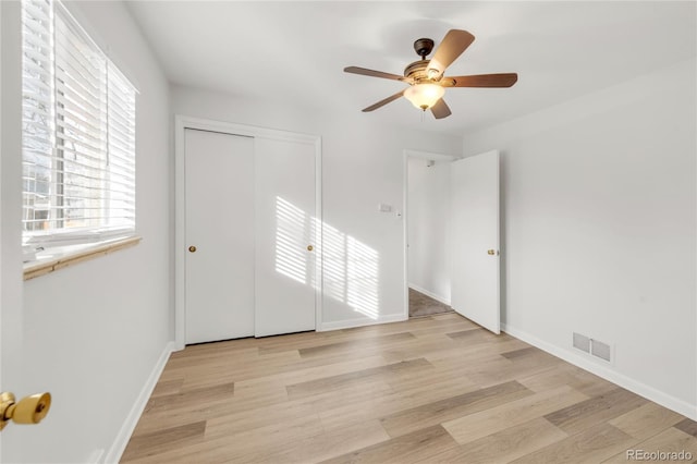 unfurnished bedroom with ceiling fan, a closet, and light wood-type flooring