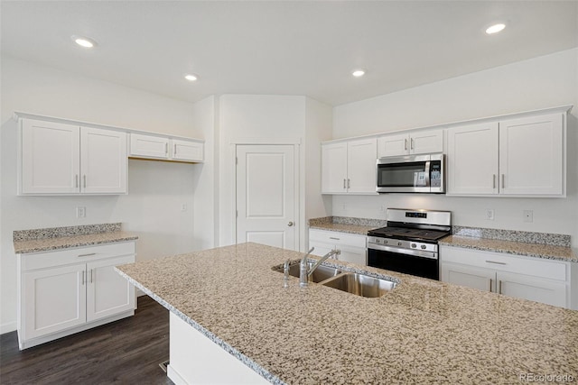 kitchen with appliances with stainless steel finishes, dark hardwood / wood-style flooring, light stone counters, sink, and white cabinets