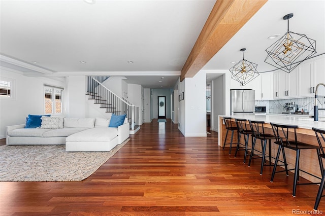 living room featuring beamed ceiling, hardwood / wood-style flooring, and an inviting chandelier