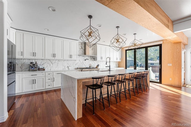 kitchen with dark hardwood / wood-style flooring, white cabinetry, a kitchen island with sink, and sink