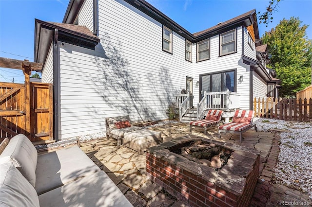 rear view of property featuring a patio area and an outdoor living space with a fire pit