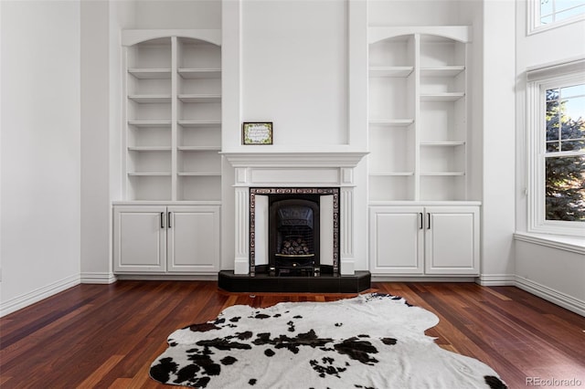 unfurnished living room with built in features, a fireplace, and dark hardwood / wood-style floors