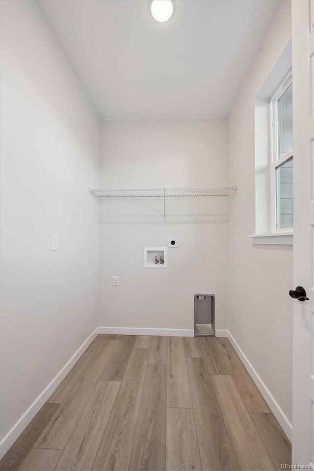 clothes washing area with light wood-type flooring, hookup for a washing machine, and hookup for an electric dryer