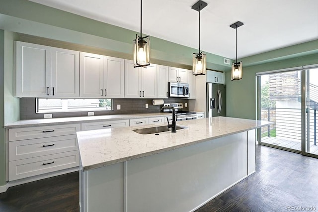 kitchen with light stone counters, stainless steel appliances, hanging light fixtures, sink, and white cabinets