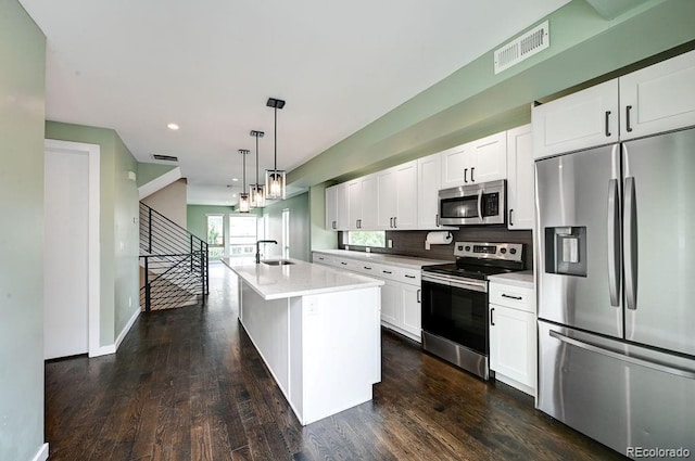 kitchen featuring white cabinets, appliances with stainless steel finishes, dark hardwood / wood-style floors, and a kitchen island with sink