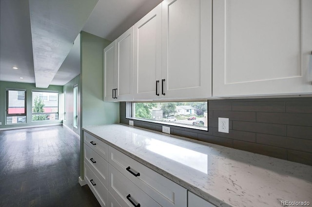 kitchen with white cabinetry, dark hardwood / wood-style flooring, tasteful backsplash, and light stone counters