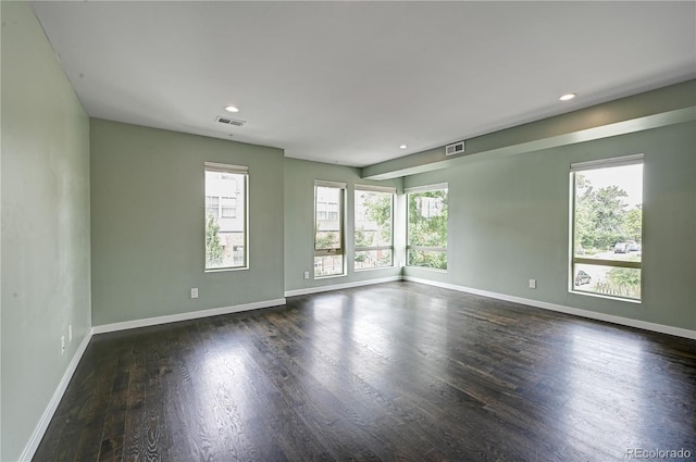 spare room with a wealth of natural light and dark hardwood / wood-style floors