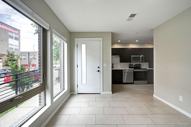 interior space with decorative backsplash, light tile patterned floors, and stainless steel appliances