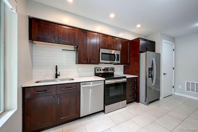 kitchen featuring light stone counters, stainless steel appliances, light tile patterned floors, decorative backsplash, and sink