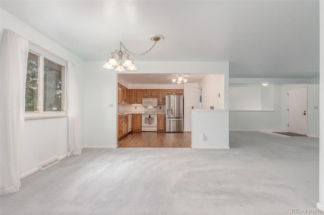 16699 E 7th Ave, Aurora, CO 80011 - unfurnished living room with a chandelier, light carpet, and ceiling fan