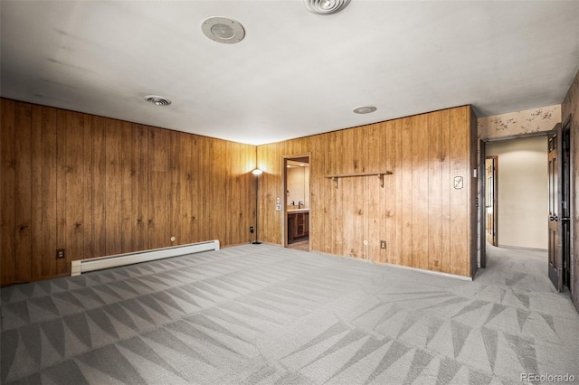 carpeted empty room featuring a baseboard radiator and wooden walls