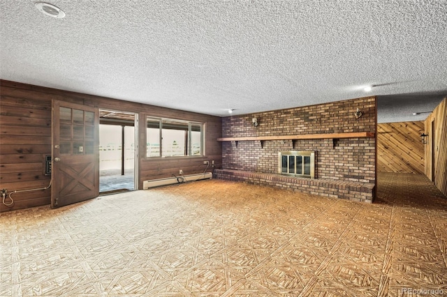 unfurnished living room featuring a brick fireplace, wood walls, a textured ceiling, and baseboard heating