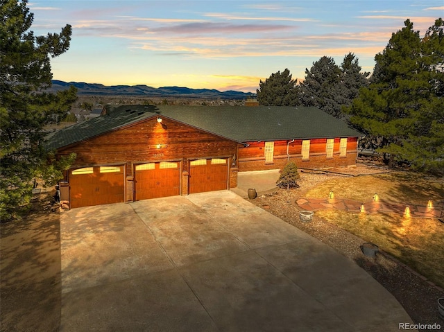 chalet / cabin featuring concrete driveway, an attached garage, and a mountain view