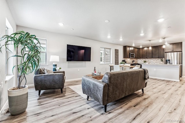 living room featuring recessed lighting, light wood-style flooring, and baseboards