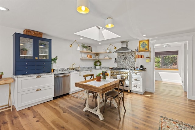 1669 Apple Valley Rd, Lyons, CO 80540 - kitchen featuring appliances with stainless steel finishes, open shelves, a skylight, a sink, and wall chimney range hood