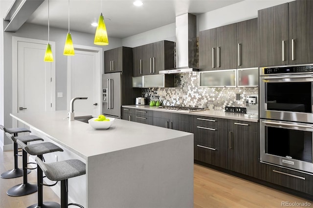 3453 Navajo St, Denver, CO 80211 - kitchen featuring stainless steel appliances, wall chimney range hood, a breakfast bar area, light countertops, and recessed lighting